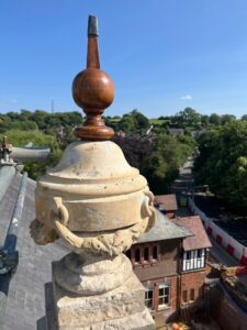 The decorative finial in place on top of the building