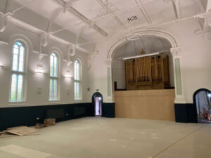 Trinity Hall plaster/ceiling repairs and redecoration are finished. The wainscotting is complete and painted, the new radiators and new uplighters are installed. It is bright and light.